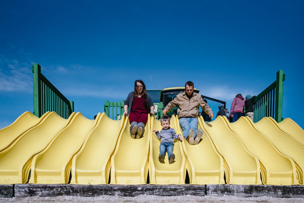 family of three sliding down slides in fall 2020