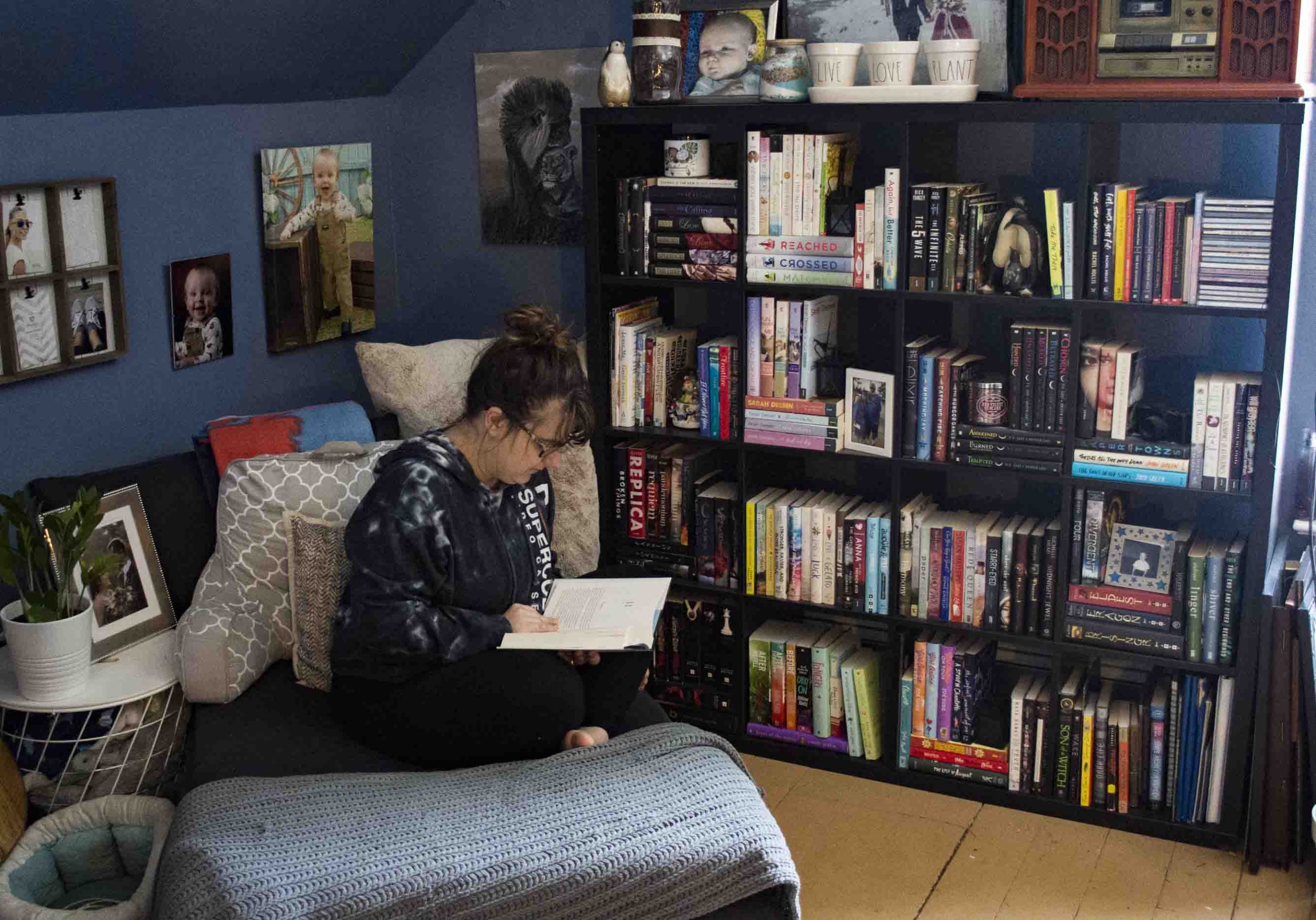 Girl reading book on chair in front of bookshelf